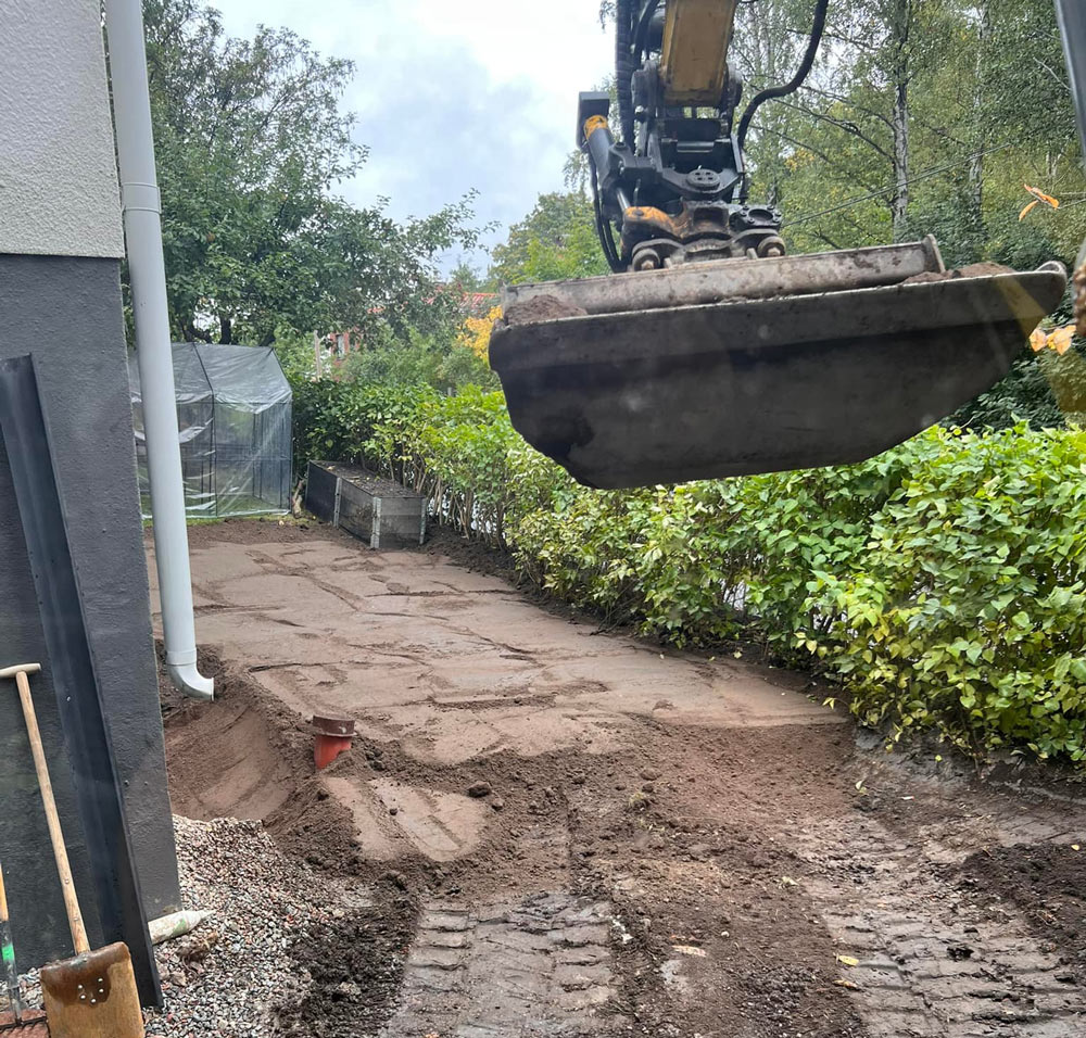 En grävskopa som gräver runt ett hus